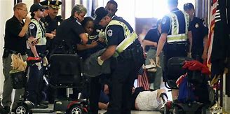 Person being taken from scooter by police at 2017 health care protest